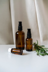 Aromatherapy concept photo with bottles with essential oils and fresh rosemary herb, vertical orientation.
