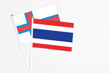 Thailand and Faroe Islands stick flags on white background. High quality fabric, miniature national flag. Peaceful global concept.White floor for copy space.