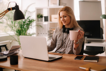 Young businesswoman in office. Beautiful woman with headphones. 