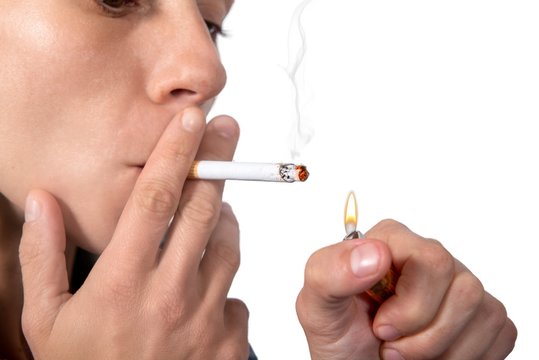 Young woman lighting cigarette on the white background