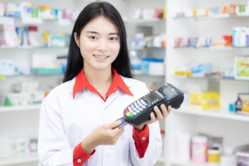 Paying with a credit card, Making purchases many medicines, Paying with a credit on many medicines shelf in pharmacy background.