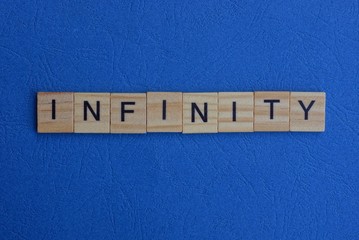 word infinity of brown wooden letters lies on a blue table