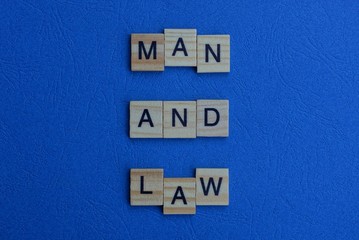the phrase man and law of brown wooden letters lies on a blue table