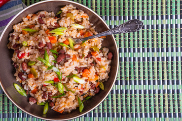 Traditional Jamaican and Mexican dish - rice with beans and vegetables and hot pepper in a bowl on a bamboo napkin, top view, copy space
