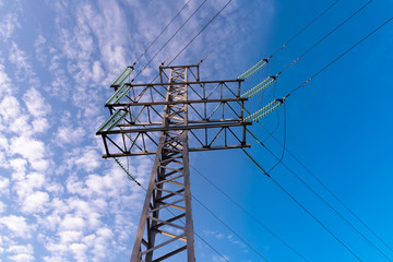 High towers of a high voltage power line against a blue sky, bottom view