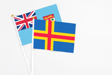 Aland Islands and Fiji stick flags on white background. High quality fabric, miniature national flag. Peaceful global concept.White floor for copy space.