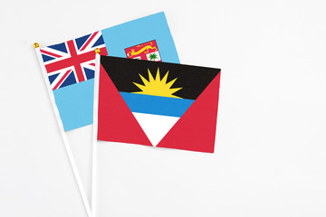 Antigua and Barbuda and Fiji stick flags on white background. High quality fabric, miniature national flag. Peaceful global concept.White floor for copy space.