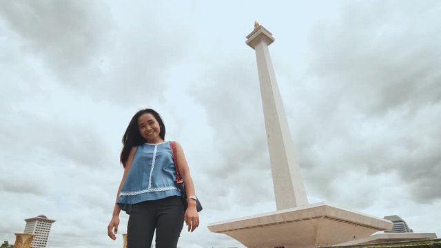 Young Indonesian girl posing on the background of the National Monument of Indonesia.