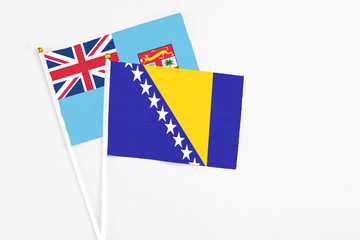 Bosnia Herzegovina and Fiji stick flags on white background. High quality fabric, miniature national flag. Peaceful global concept.White floor for copy space.