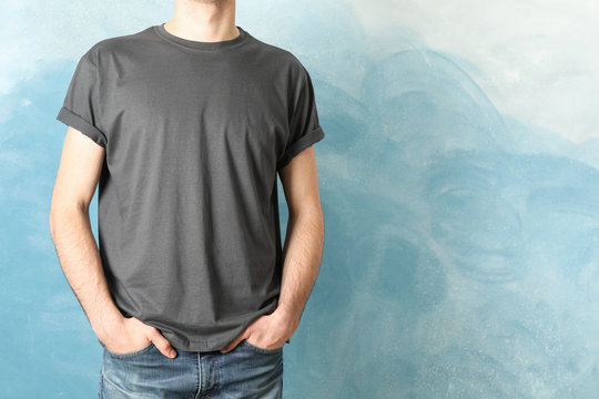 Men in blank grey t-shirt against blue background, space for text