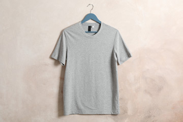 Hanger with blank gray t-shirt on brown background, space for text