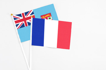 France and Fiji stick flags on white background. High quality fabric, miniature national flag. Peaceful global concept.White floor for copy space.