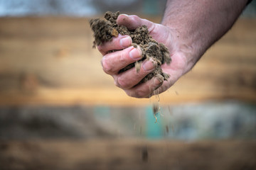 Sifting with hands and pouring dirt and sand at field