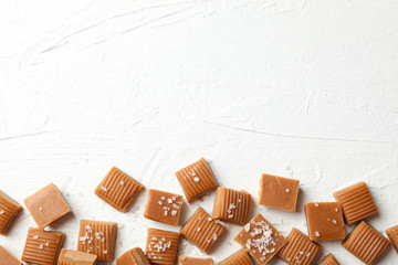 Salted caramel candies on white cement background, space for text
