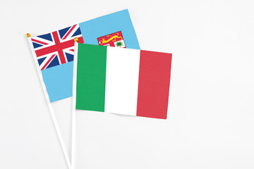 Italy and Fiji stick flags on white background. High quality fabric, miniature national flag. Peaceful global concept.White floor for copy space.