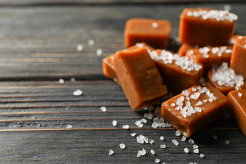 Salted caramel candies on wooden background, space for text