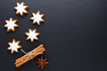 star cookies on black background with cinnamon, anise and copy space