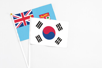 South Korea and Fiji stick flags on white background. High quality fabric, miniature national flag. Peaceful global concept.White floor for copy space.
