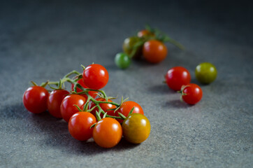 Cherry tomatoes on the vine on black stone background. Concept for healthy nutrition. Symbolic image. Copy space.