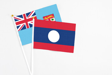 Laos and Fiji stick flags on white background. High quality fabric, miniature national flag. Peaceful global concept.White floor for copy space.