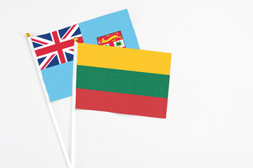 Lithuania and Fiji stick flags on white background. High quality fabric, miniature national flag. Peaceful global concept.White floor for copy space.