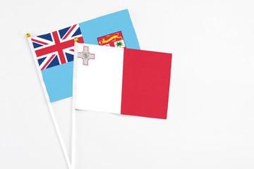 Malta and Fiji stick flags on white background. High quality fabric, miniature national flag. Peaceful global concept.White floor for copy space.