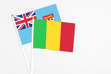 Mali and Fiji stick flags on white background. High quality fabric, miniature national flag. Peaceful global concept.White floor for copy space.