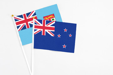 Fototapeta premium New Zealand and Fiji stick flags on white background. High quality fabric, miniature national flag. Peaceful global concept.White floor for copy space.
