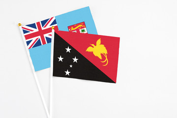 Papua New Guinea and Fiji stick flags on white background. High quality fabric, miniature national flag. Peaceful global concept.White floor for copy space.