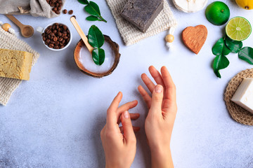 Natural cosmetic products setting with soaps and fresh herbs top view woman hands