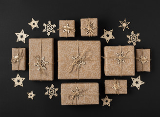 Christmas gifts in paper packaging on a black background. Concept: packaging and decor from recyclable eco-natural materials.