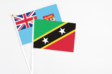 Saint Kitts And Nevis and Fiji stick flags on white background. High quality fabric, miniature national flag. Peaceful global concept.White floor for copy space.