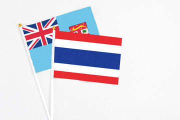 Thailand and Fiji stick flags on white background. High quality fabric, miniature national flag. Peaceful global concept.White floor for copy space.