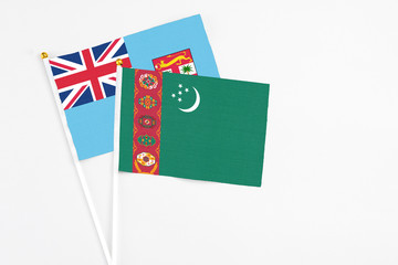 Turkmenistan and Fiji stick flags on white background. High quality fabric, miniature national flag. Peaceful global concept.White floor for copy space.