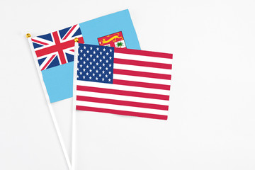 United States and Fiji stick flags on white background. High quality fabric, miniature national flag. Peaceful global concept.White floor for copy space.
