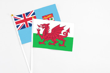 Wales and Fiji stick flags on white background. High quality fabric, miniature national flag. Peaceful global concept.White floor for copy space.