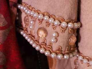 Close up detail on sleeve of a pink costume decorated with pearls and gemstone for theatre performances