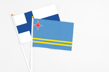 Aruba and Finland stick flags on white background. High quality fabric, miniature national flag. Peaceful global concept.White floor for copy space.