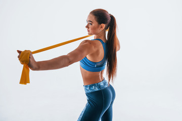 With yellow resistance band. Young woman with slim body type isolated against white background