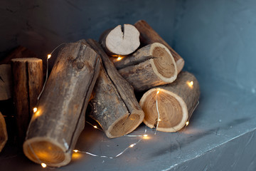 Logs of a tree are located on the wall. Imitation of a fireplace in the wall, lights of a garland with logs