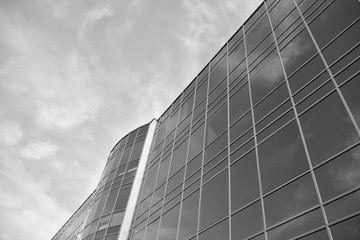 Fototapeta na wymiar Curtain wall made of toned glass and steel constructions under sky. A fragment of a building. Black and white.