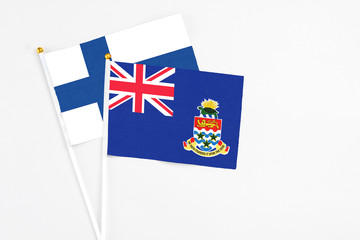 Fototapeta premium Cayman Islands and Finland stick flags on white background. High quality fabric, miniature national flag. Peaceful global concept.White floor for copy space.