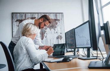 Analyzing information together. Two stockbrokers in formal clothes works in the office with financial market