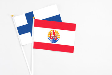 French Polynesia and Finland stick flags on white background. High quality fabric, miniature national flag. Peaceful global concept.White floor for copy space.