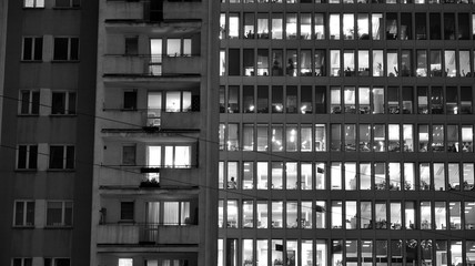 Obraz premium Pattern of office buildings windows illuminated at night. Lighting with Glass architecture facade design with reflection in urban city. Black and white.