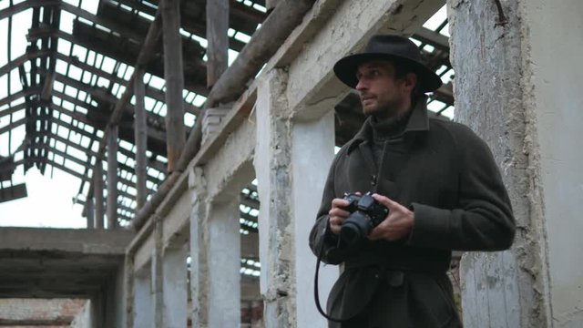 Photographer with coat and hat at old place taking some photos