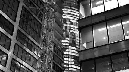 Obraz premium Pattern of office buildings windows illuminated at night. Lighting with Glass architecture facade design with reflection in urban city. Black and white.