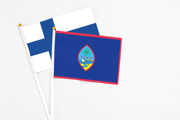 Guam and Finland stick flags on white background. High quality fabric, miniature national flag. Peaceful global concept.White floor for copy space.