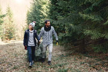 Cheerful dad and his son carrying the christmas tree