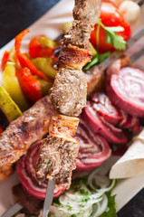 Assorted meat kebabs with vegetables and spices.